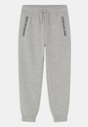 Pantalon de survêtement gris clair avec ceinture élastique et poignets, cordon de serrage à l'avant, et logos « Calvin Klein Jeans » sur les bords des poches.