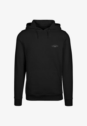 Črna kapuca iz mehkega blaga s sprednjo žepom in vrvicami. Minimalističen dizajn z izvezenim napisom "DEMON INSIDE" na prsih.