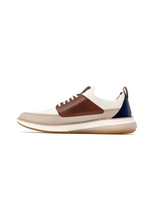 Niedrig geschnittene Sneaker mit beigem Strick-Obermaterial, braunem Lederüberzug, marineblauem Fersenpatch, weißen Schnürsenkeln und beiger Gummisohle.