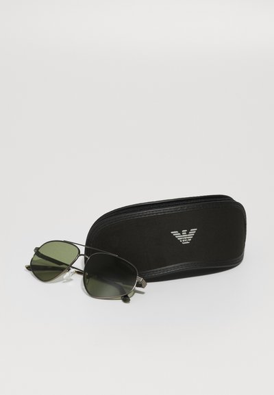 Metal aviator sunglasses with green lenses and a black zippered case featuring a silver logo on the front. Case has a soft texture.