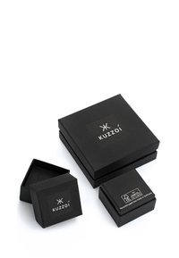 Black cardboard gift boxes of various sizes, featuring a "Kuzzoi" logo. The texture is smooth, with a minimalist design and no visible patterns.
