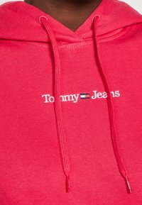 Felpa rossa con cappuccio, con logo "Tommy Jeans" ed emblema della bandiera ricamati sul petto, dotata di spesse stringhe.