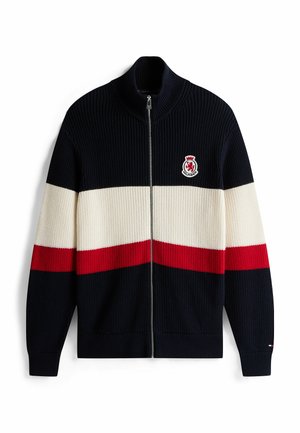 Cardigan lavorato a maglia con zip nei colori blu navy, crema e strisce rosse. Presenta un colletto alto e una patch con logo sul lato sinistro. Texture a costine.
