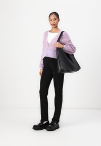 Borsa a tracolla nera, cardigan lavanda lavorato a maglia con dettagli decorati, top bianco e pantaloni neri aderenti abbinati a scarpe chunky nere.