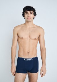 Navy blue boxer briefs with a white waistband featuring the "DIESEL" logo. Smooth fabric and fitted design, worn by a male model.