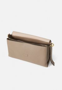 Beige Leder Umhängetasche mit gefaltetem Deckel, ausgestattet mit einem ringförmigen goldenen Beschlag und einer glatten Oberfläche. Einfaches Design ohne sichtbare Muster.