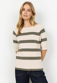 Ribbed knit-sweateri, jossa on beige ja oliivinvihreät vaakasuorat raidat, pyöreä pääntie ja lyhyet hihat. Yhdistetty tummiin farkkuihin.