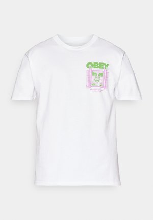 Hvit bomull t-skjorte med et grønt og rosa grafisk design på forsiden, inkludert teksten "OBEY" og et stilisert ansikt innenfor en ramme.