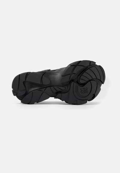Sole di scarpa sportiva nera in materiale gommoso testurizzato, con un motivo di battistrada unico per aderenza e stabilità, forma arrotondata con accenti curvi.