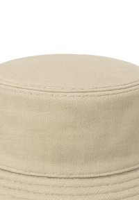 Cappello a secchiello beige con tessuto liscio e strutturato. Il cappello presenta una cima arrotondata e una fascia cucita uniformemente intorno alla corona.