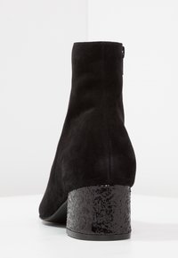 Schwarze Wildleder-Ankelstiefel mit einem strukturierten schwarzen Glitzer-Blockabsatz, glattem Obermaterial und eleganter Silhouette. Reißverschlussdetail auf der Rückseite.