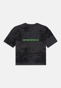 Svart t-skjorte med korte ermer som har et teksturert mønster. Inkluderer en dristig svart rektangulær logo med "EA7" og "EMPORIO ARMANI" i grønt.