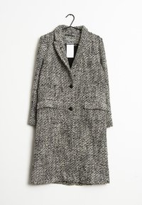 Abrigo de patrón de espiga en blanco y negro, con cuello de muesca, dos bolsillos frontales y dos botones negros. Fabricado en un tejido texturizado.