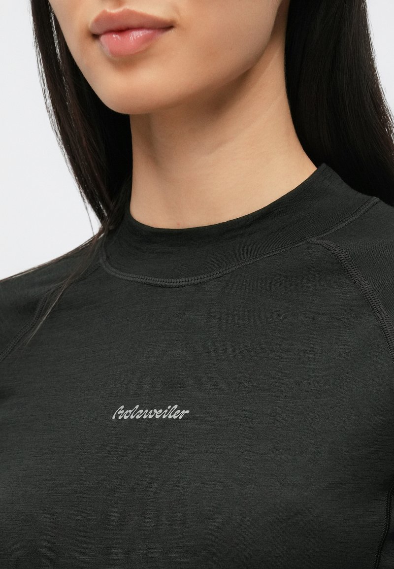 Close-up of a person wearing a black top with visible stitching and small white text logo centered on the chest.
