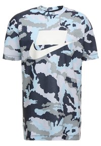 Kortärmad t-shirt med kamouflage-mönster i nyanser av blått och grått, med en stor vit Nike-logotyp på framsidan, tillverkad av andningsbart tyg.