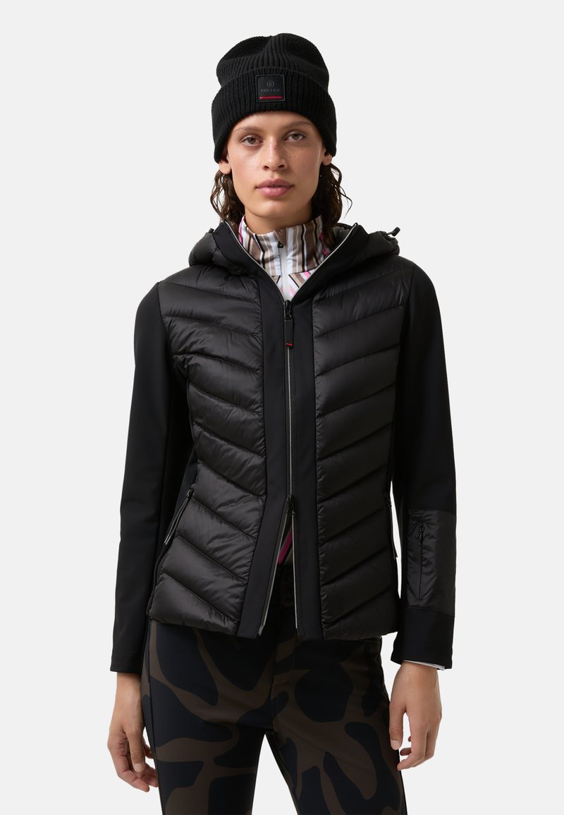 Czarna hybrydowa kurtka z miękkim, pikowanym przodem, gładkimi rękawami, kapturem i kieszeniami na zamek. W połączeniu z wzorzystymi legginsami.