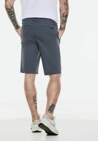 Shorts gris en matériau léger, avec une coupe régulière, des poches avant et arrière, et des détails de couture discrets.
