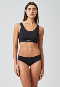 Soutien-gorge de sport noir en coton avec un décolleté arrondi et une bande logo blanche ; assorti à une culotte noire à bordures en dentelle.