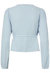 Blouse bleu clair à manches longues vue de dos, tissu légèrement texturé et taille cintrée. Aucun fermoir ou ornement visible.