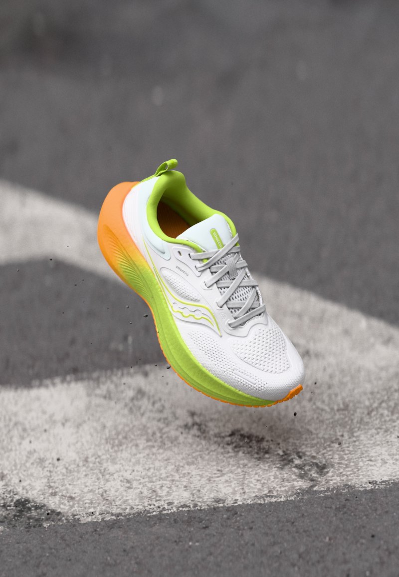 Chaussure de course avec une tige en mesh blanc, des accents vert lime et un talon orange. Comprend un col rembourré et une semelle extérieure texturée pour une meilleure adhérence.