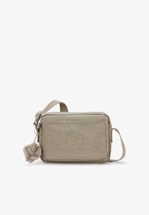 Bolso bandolera beige con tejido texturizado, cierre de cremallera y un bolsillo frontal. Cuenta con un logo redondo y un detalle de llavero peludo.