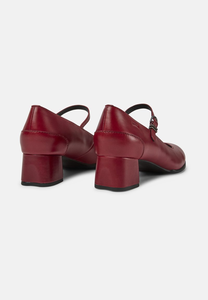 Czerwone skórzane buty Mary Jane z niskimi obcasami oraz klamrami, pokazane z tyłu na białym tle.