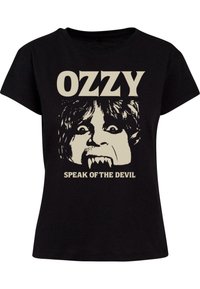 Juodas medvilninis marškinėliai su grafiniu spaudiniu, vaizduojančiu veidą su iltimis ir užrašu "OZZY SPEAK OF THE DEVIL" kreminės spalvos šriftu.