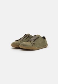Scarpe in suede verde oliva con profilo basso, punta arrotondata e soletta in gomma. Presentano chiusura con lacci e dettagli di cucitura minimi.