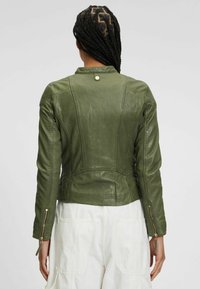 Olivgrüne Lederjacke mit figurbetontem Design, ausgestattet mit Reißverschluss-Manschetten, Nahtdetails und einem Druckknopfverschluss am oberen Kragen.