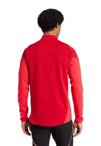 Rotes langärmliges Sportshirt mit glatter Textur, hohem Kragen und kontrastierenden Akzenten an den Ärmeln, entworfen für Leistung und Komfort.
