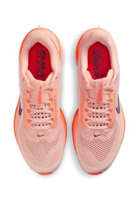 Un par de zapatillas de correr Nike Pegasus en color rosa con suelas naranjas y plantillas rojas etiquetadas como "Air Zoom", vistas desde arriba.