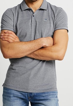 Polo gris avec col, manches courtes et petit logo sur la poitrine. Tissu texturé avec bordure contrastante sur les manches.