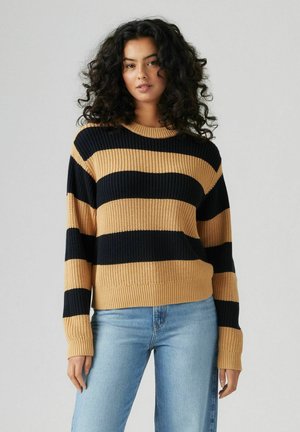 Cream and navy striped knit sweater with ribbed texture, round neck, and long sleeves, paired with light blue jeans.