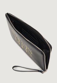 Sort læder clutch med lynlås, guldfarvet logo print foran og en håndledsrem. Indvendigt har den kortlommer og en tekstureret foring.