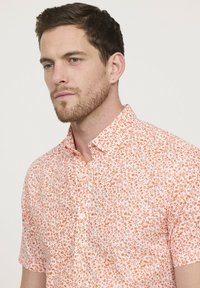 Korte mouwen overhemd met knopen in lichtroze met een oranje bloemenpatroon, voorzien van een klassieke kraag en een zachte, gladde textuur.