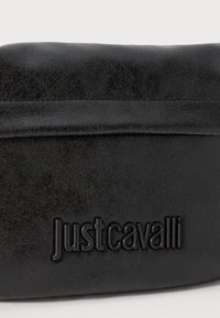Borsa nera in ecopelle con texture liscia. Presenta un discreto logo "Just Cavalli" in rilievo sulla parte frontale e una cucitura lungo la parte superiore.