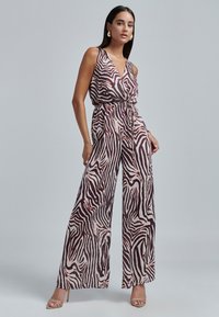 Braunes und cremefarbenes Zebra-Print-Overall mit V-Ausschnitt, verstellbarem Taillengürtel, weitem Bein und goldfarbigen Akzenten. Glatte Stofftextur.