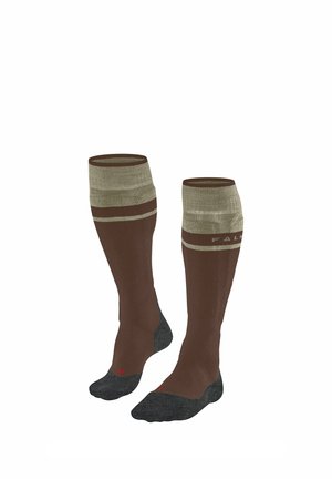 Par af lange brune sokker med beige topbånd og mørkegrå hæle og tæer vist oprejst på en hvid baggrund.