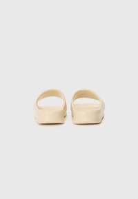 Krämfärgade slip-on sandaler med öppen häl. Tillverkade av slät plast, med rundade kanter och en minimalistisk design.