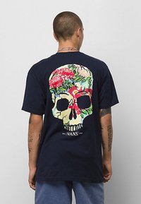Marinblå bomulls t-shirt med en stor floral dödskalle grafik på ryggen. Rund hals, korta ärmar, avslappnad passform, med subtil textdetalj.