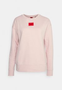 Felpa rosa chiaro in cotone con maniche lunghe, collo tondo e patch rettangolare rosso con la scritta "HUGO" sul davanti.