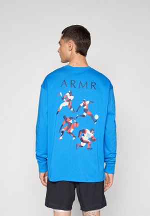 Blauw T-shirt met lange mouwen met een grafiek van dynamische atleten op de achterkant en de tekst "ARMR" boven het ontwerp.
