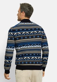 Strickpullover in Blau und Schwarz mit geometrischen Mustern. Verfügt über gerippte Bündchen und Saum sowie ein hohes Kragen-Design. Weiche Textur.