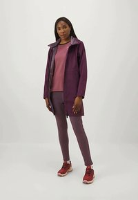 Purple zip-up jacket with a fleece-lined collar, layered over a pink top and matching fitted pants. Red sneakers complete the outfit.