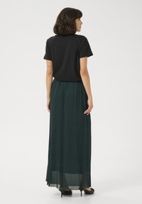 T-shirt nero a maniche corte abbinato a una gonna plissettata a lunghezza intera di un verde scuro. La gonna presenta un tessuto testurizzato e una silhouette fluida.