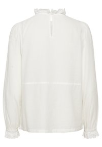 Vit långärmad blus tillverkad av ett lätt tyg, med en volangkrage, knäppning bak och spetsdetaljer vid ärmsluten.