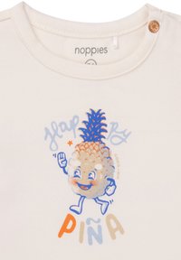 Crème kleurig katoenen t-shirt met een speelse ananas graphic met blauwe en oranje accenten en een drukknoopje bij de hals.