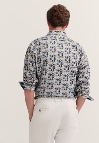 Blumenmuster-Hemd mit einem blau-, weiß- und braunfarbenen Design. Button-Down-Kragen, lange Ärmel, aufgerollte Manschetten und leichtes Material.