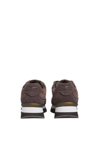 Des baskets en daim marron avec une semelle intermédiaire blanche rembourrée, des accents texturés et des détails en métal doré. Conçues pour le confort et le soutien.