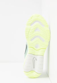 Suela de zapato deportivo Nike que presenta una base blanca con una suela amarilla texturizada. Incluye un logotipo prominente y un patrón de relieve distintivo.